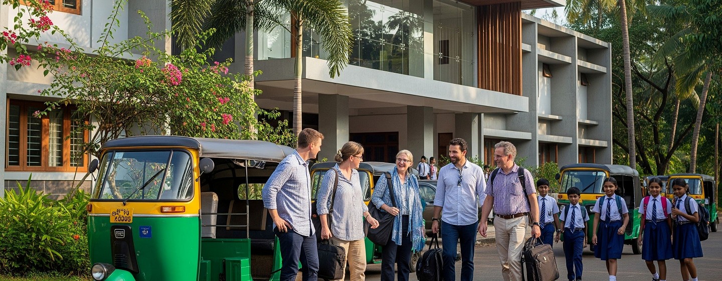 english teachers stood in front of a tuk tuk outside a school in india